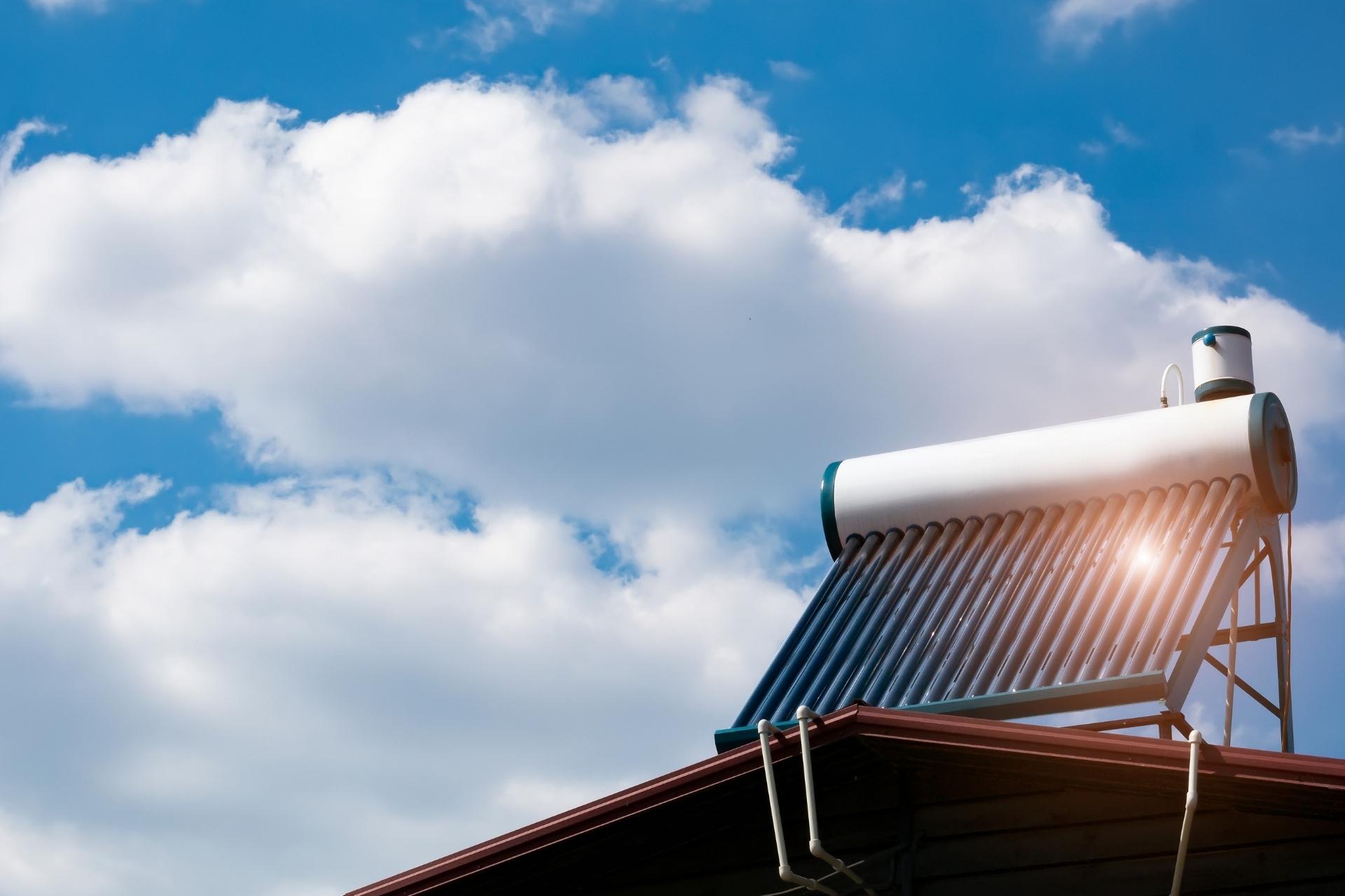 Image montrant un Ballon d'eau solaire installé sur le toit d'une maison. Le chauffe-eau est composé d'un large réservoir et de panneaux solaires thermiques de couleur bleu-vert. L'image illustre l'utilisation de l'énergie solaire pour la production d'eau chaude dans cette maison.